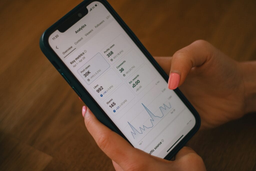 Close-up of a person holding a smartphone displaying social media analytics and key metrics